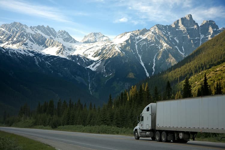 Truck driving on the road with snowy mountains in the background